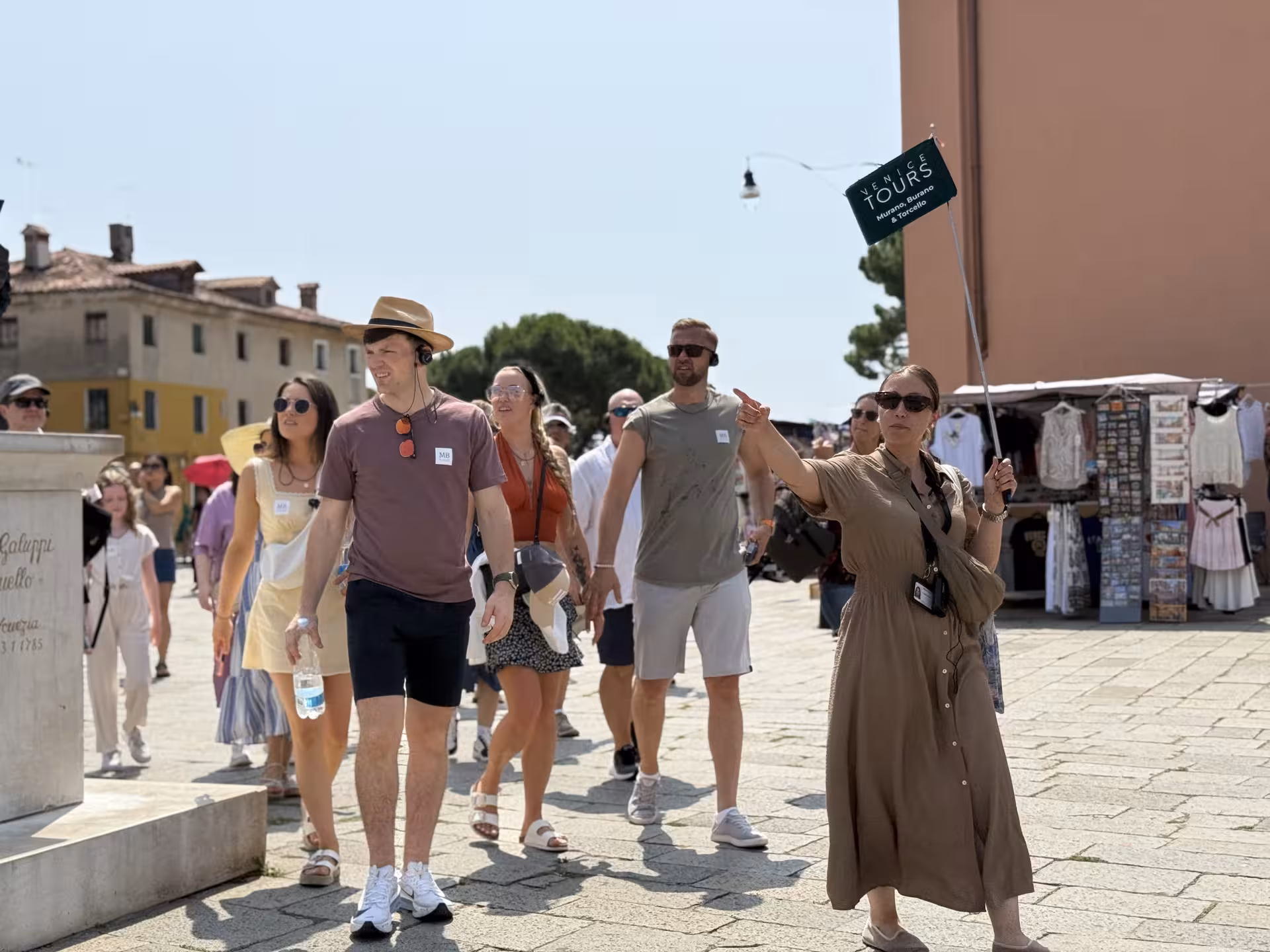 Tour guide leads a group through Venice, highlighting attractions on the Grand Tour, including Murano and Burano.