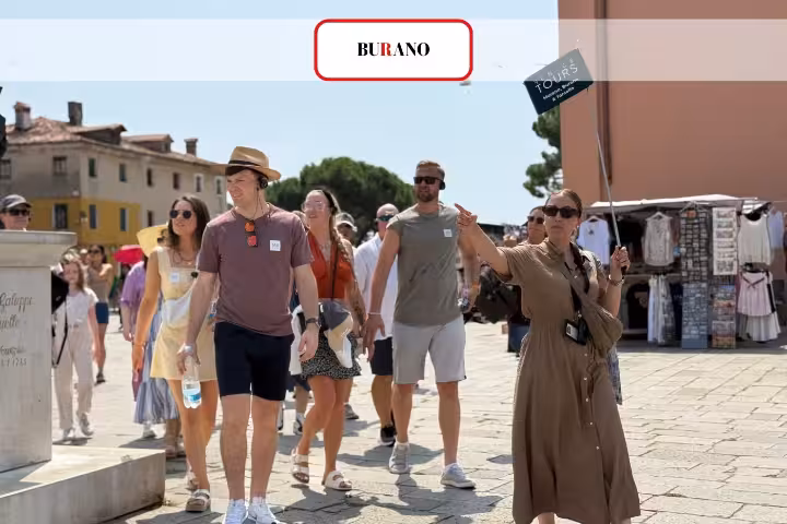 Tour group exploring colorful Burano island on Venice Islands Guided Cruise with local guide leading the way.