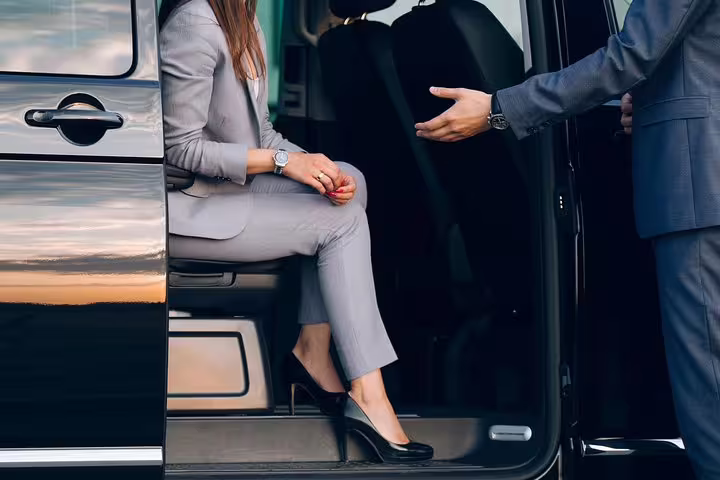Professional chauffeur assisting a businesswoman during a private transfer from Venice Marco Polo airport.