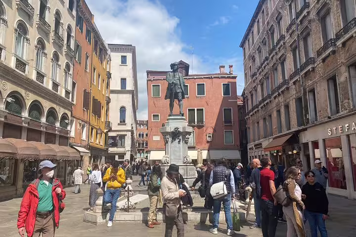 Tourists exploring a lively Venice piazza with a historic statue during a sightseeing walking tour