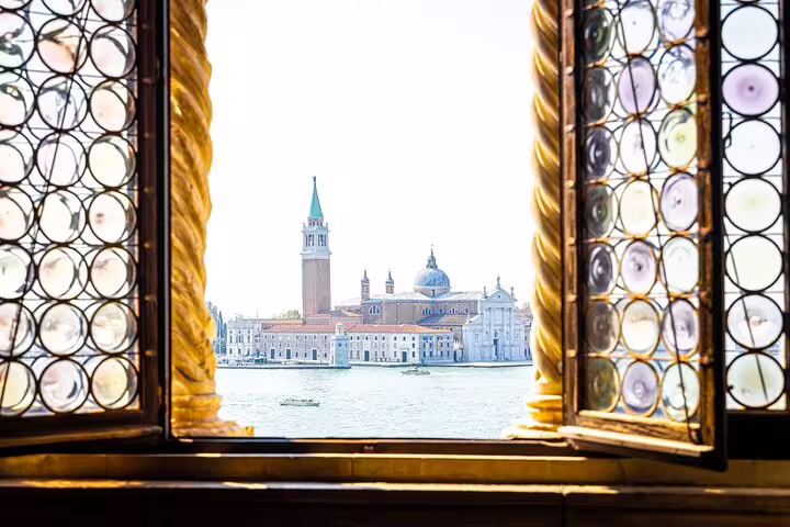 Scenic view of San Giorgio Maggiore island framed by ornate palace window on an exclusive off the beaten path Venice tour
