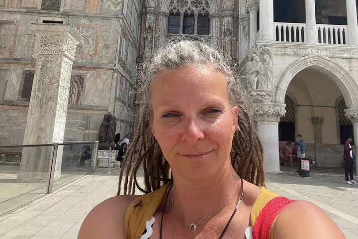 Smiling woman with dreadlocks taking selfie in front of ornate Venice Gothic cathedral facade