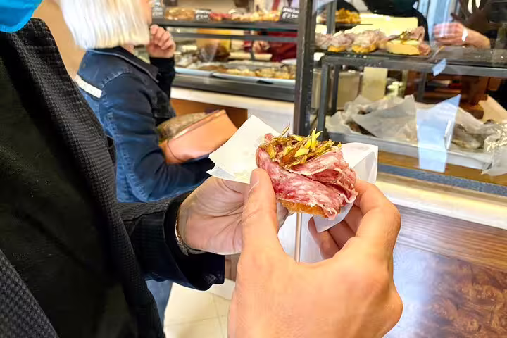 Traveler holding a traditional Venetian cicchetti sandwich during a Venice street food and sightseeing walking tour