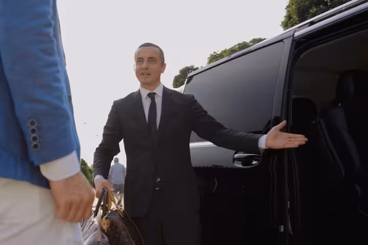 Professional chauffeur greeting passenger for Venice to Treviso Airport transfer in luxury vehicle.