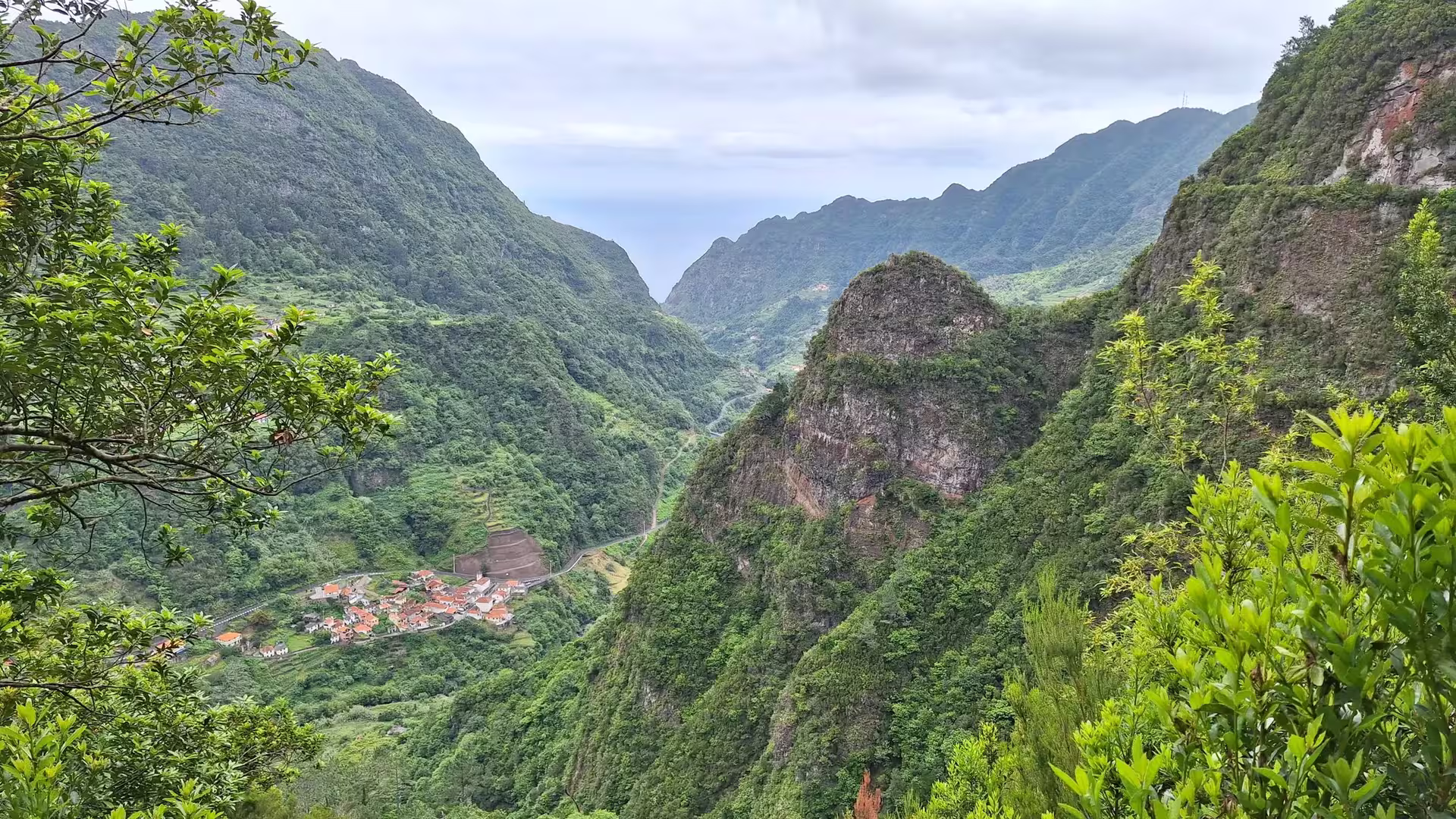 Panoramic view of verdant mountain valley and quaint village, perfect for an untouched nature hike.