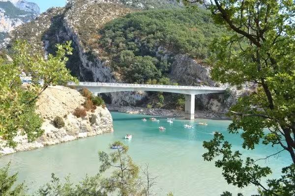 Turquoise waters of Verdon Canyon with a modern bridge and kayakers surrounded by rocky cliffs, Provence