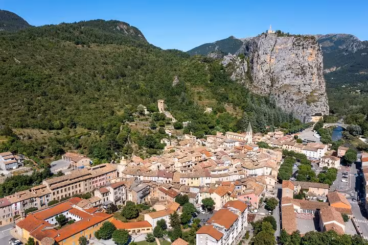 Aerial view of a medieval Provençal village nestled among green hills and dramatic limestone cliffs in Verdon region
