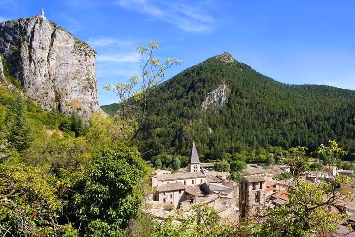 Medieval village with stone church nestled among green hills and dramatic limestone cliffs in Verdon region