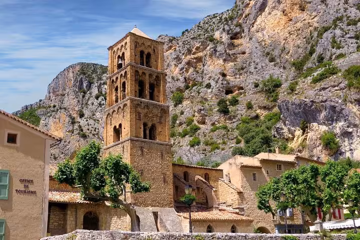 Medieval stone church tower in Moustiers-Sainte-Marie village with limestone cliffs backdrop, Verdon region France
