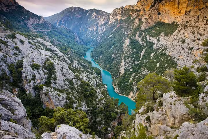 Turquoise waters of Verdon Gorge winding through steep limestone cliffs and lush green forests
