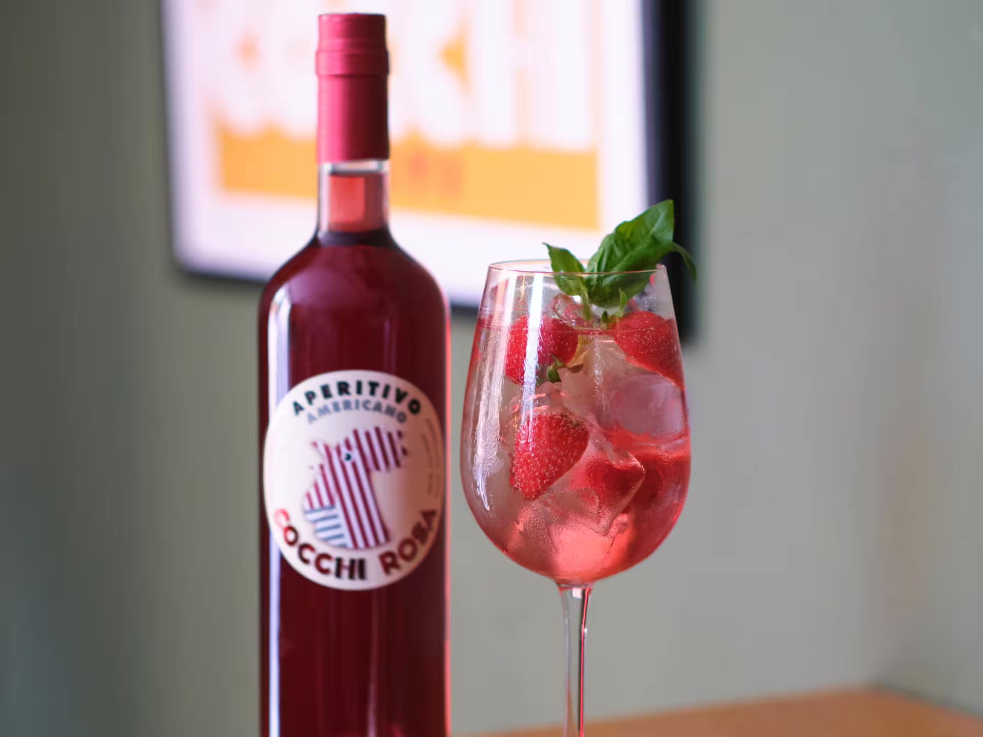 Refreshing vermouth cocktail with strawberries and basil beside a bottle of Cocchi Rosa in Turin tasting event.