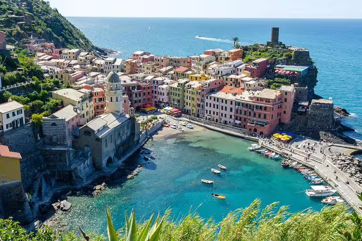 Colorful Vernazza harbor on the Ligurian coast with boats, clear turquoise sea and historic church on a Gulf of Poets private tour