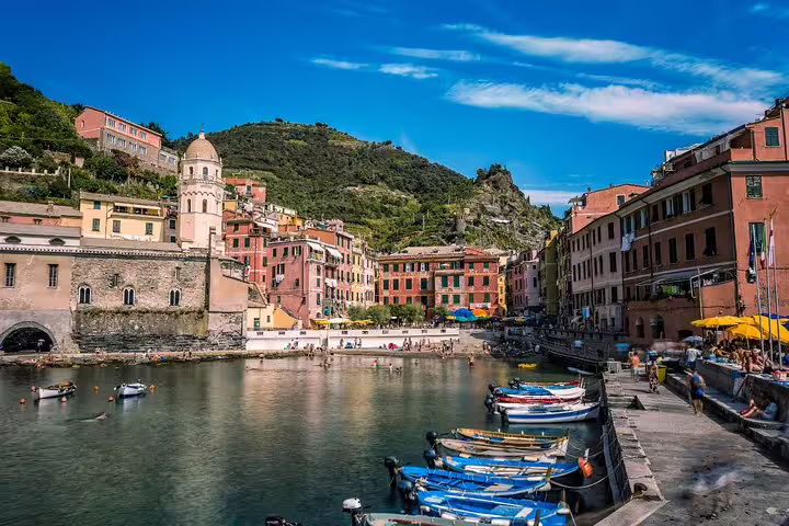 Vernazza harbor with boats, historic church and pastel buildings backed by green hills on a private Cinque Terre tour