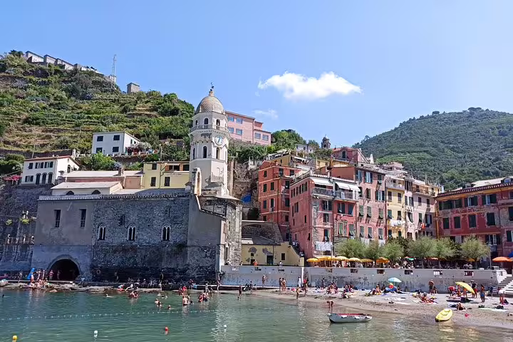 Vernazza harbor in Cinque Terre with church tower, beachgoers and colorful houses on a one day private tour from Porto Venere