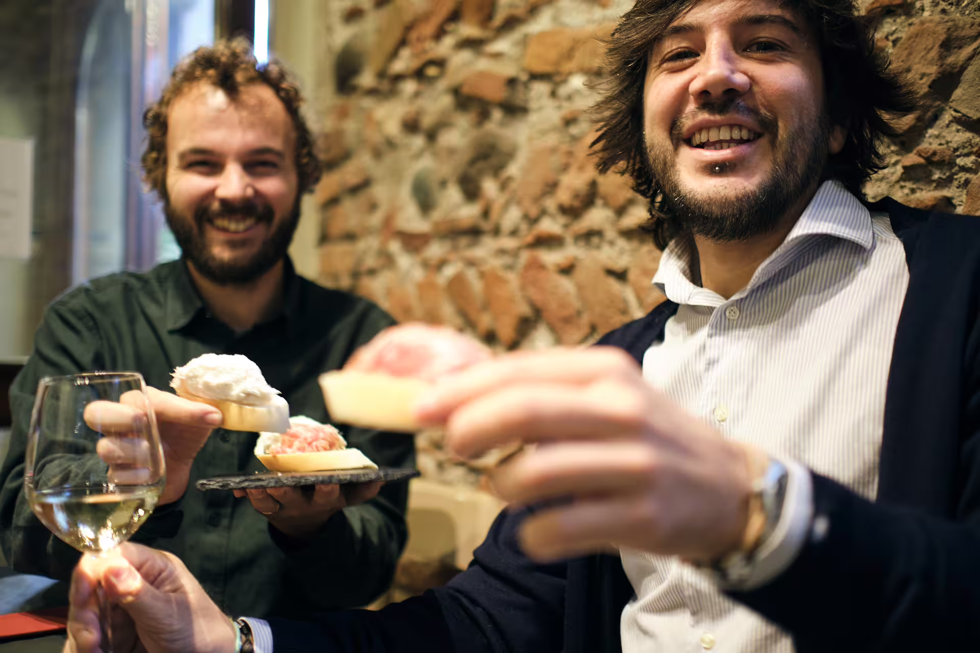Guests enjoy cicchetti bites and white wine on guided Verona food tour, tasting local cheeses and salumi