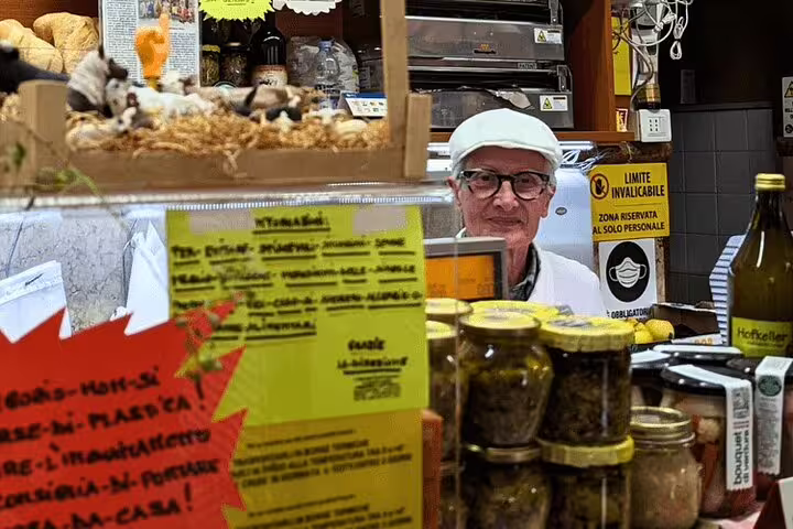 Verona market stall vendor on guided food tour, sampling local specialties with wine tasting in Italy
