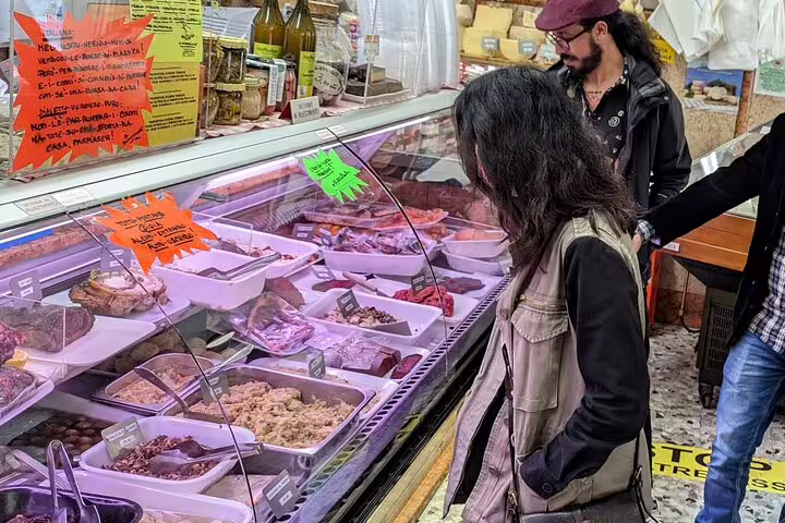 Travelers browse a Verona market deli counter for local specialties on a guided food tour with wine tasting