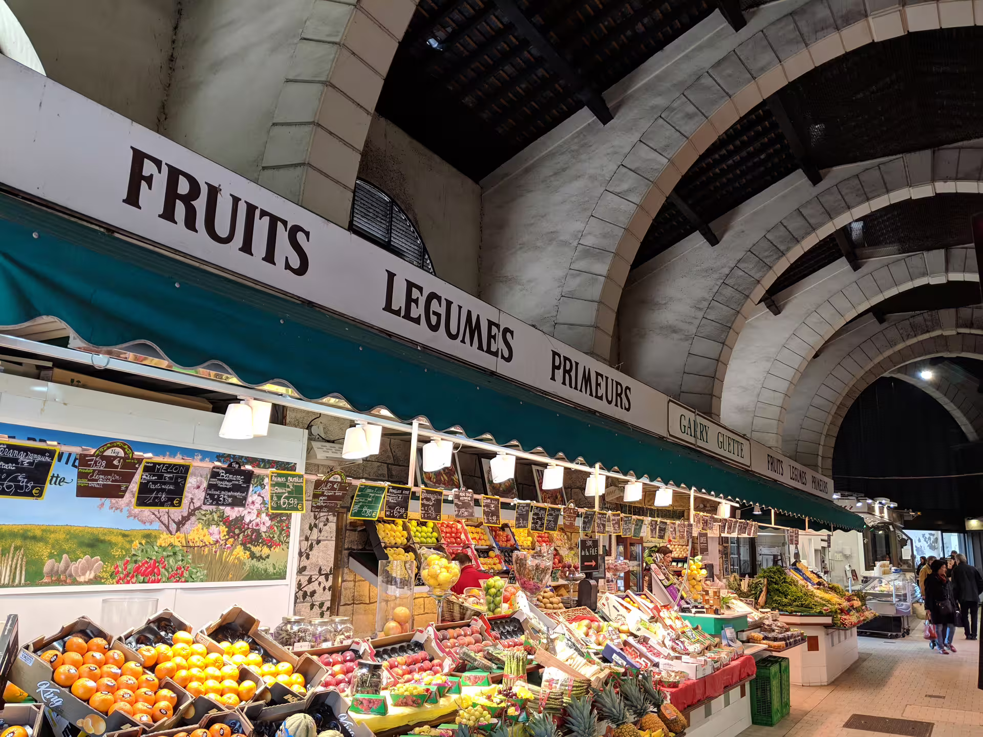 Colorful fruit and vegetable stalls inside a covered market hall in Versailles, France