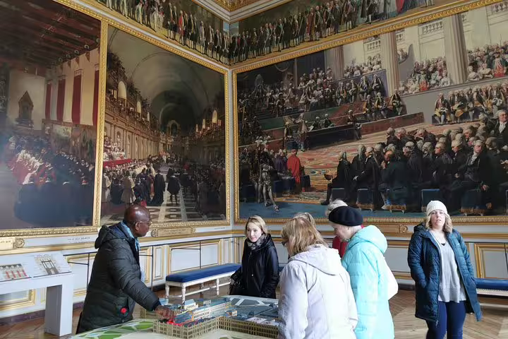 Visitors explore Versailles Palace gallery murals on a full-day private guided tour with hotel pickup from Paris