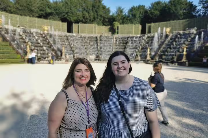 Guests posing by the fountains in the Palace of Versailles gardens on a full-day private guided tour with pickup