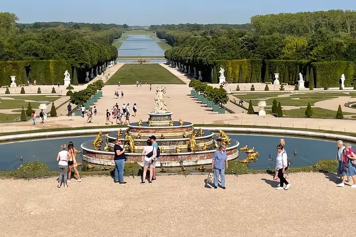 Latona Fountain at Palace of Versailles gardens with tourists and grand canal perspective