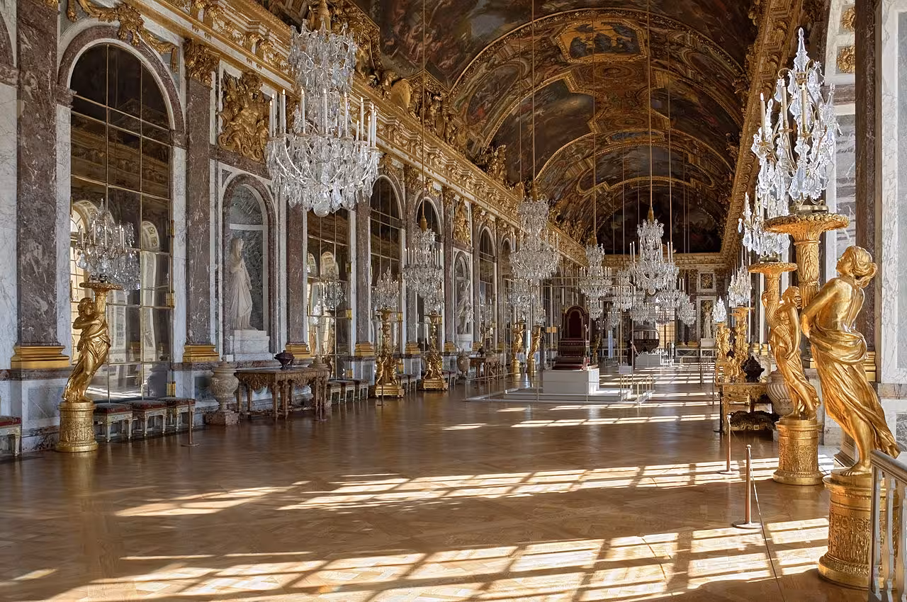 Hall of Mirrors at Palace of Versailles with crystal chandeliers, gilded statues, and painted vaulted ceiling