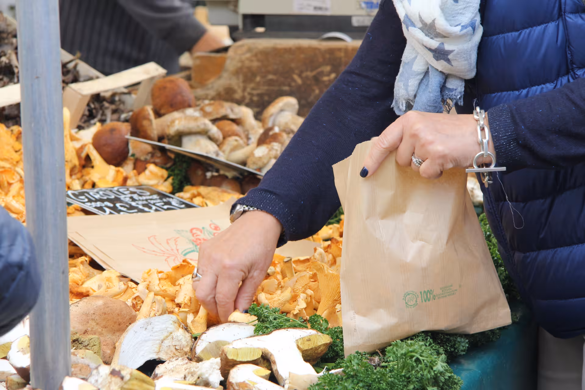 Woman selecting fresh wild mushrooms and chanterelles at a Versailles outdoor food market