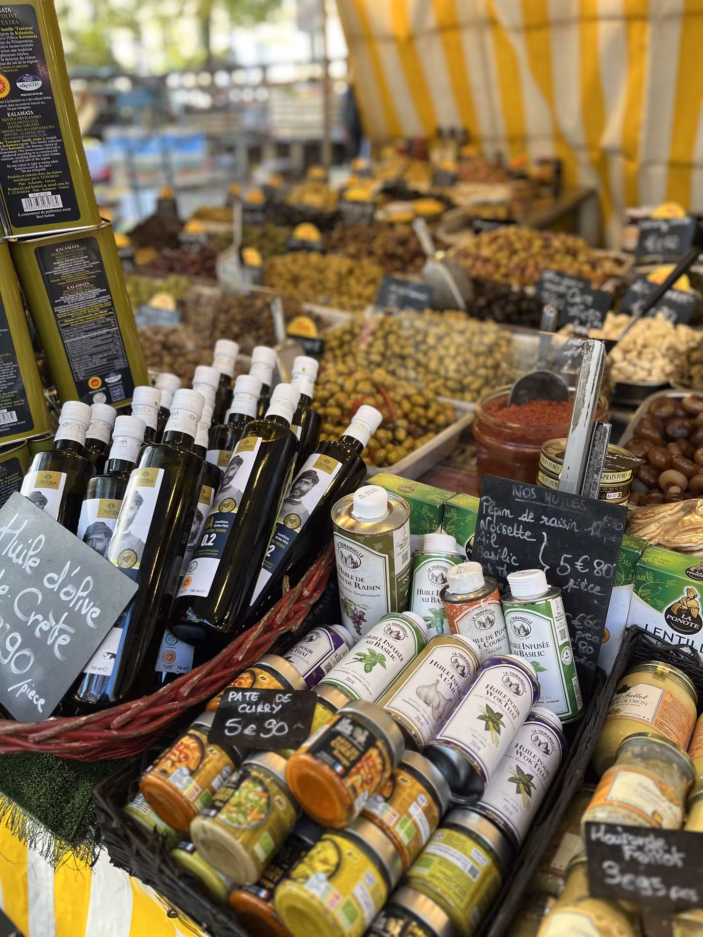 French market stall with olive oils, olives, and specialty foods at Versailles outdoor market