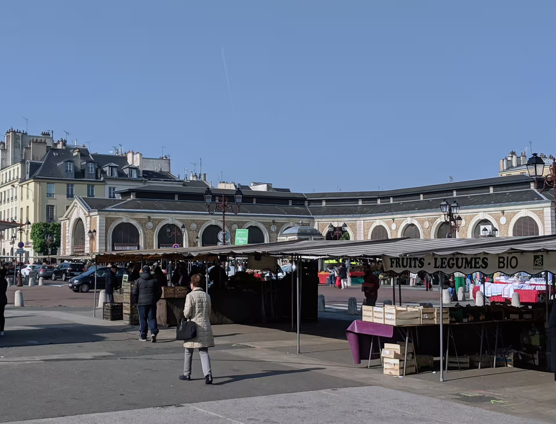 Outdoor organic fruits and vegetables market stalls in front of the historic Versailles market hall
