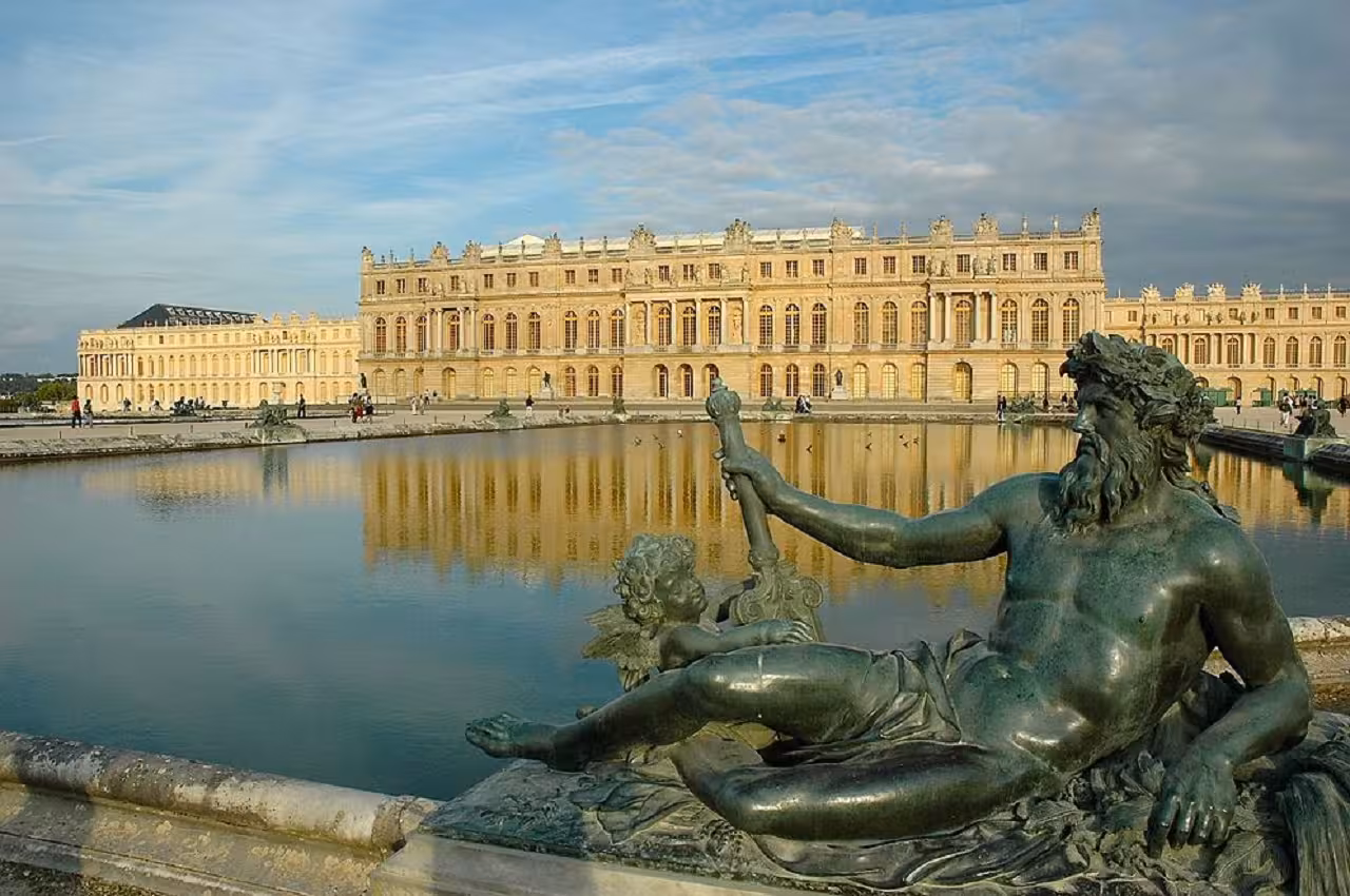 Bronze reclining river god statue beside reflecting pool at Palace of Versailles gardens