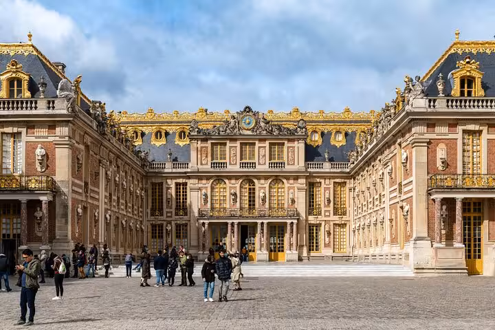 Versailles Palace courtyard facade with gold trim and visitors, perfect for a guided grand tour experience