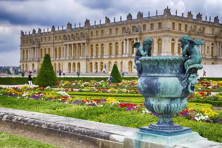 Versailles Palace facade and colorful formal gardens with ornate urn, seen on guided skip-the-line tour