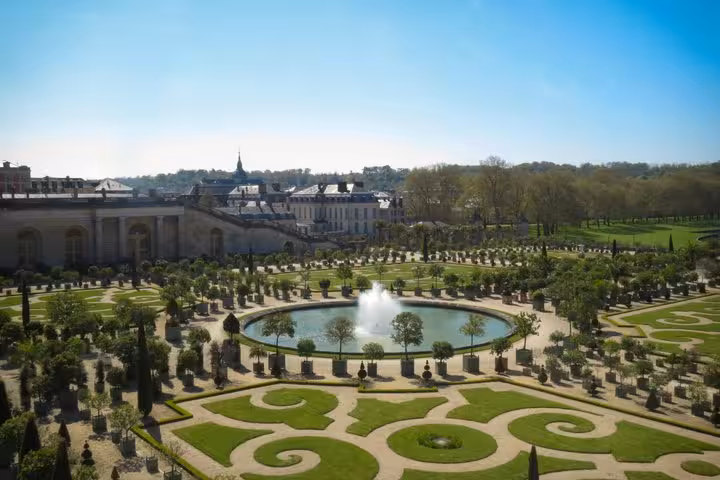 Aerial view of Palace of Versailles ornate formal gardens with circular fountain and manicured hedgerows
