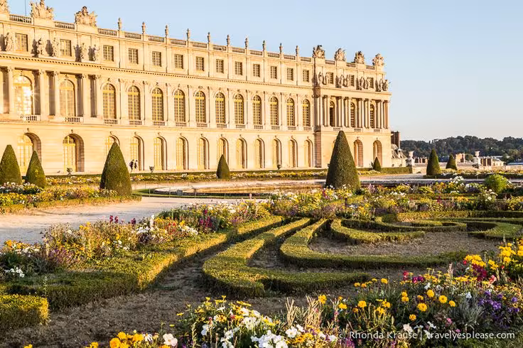 Palace of Versailles facade and formal parterre gardens in golden light on a Versailles Grand Tour