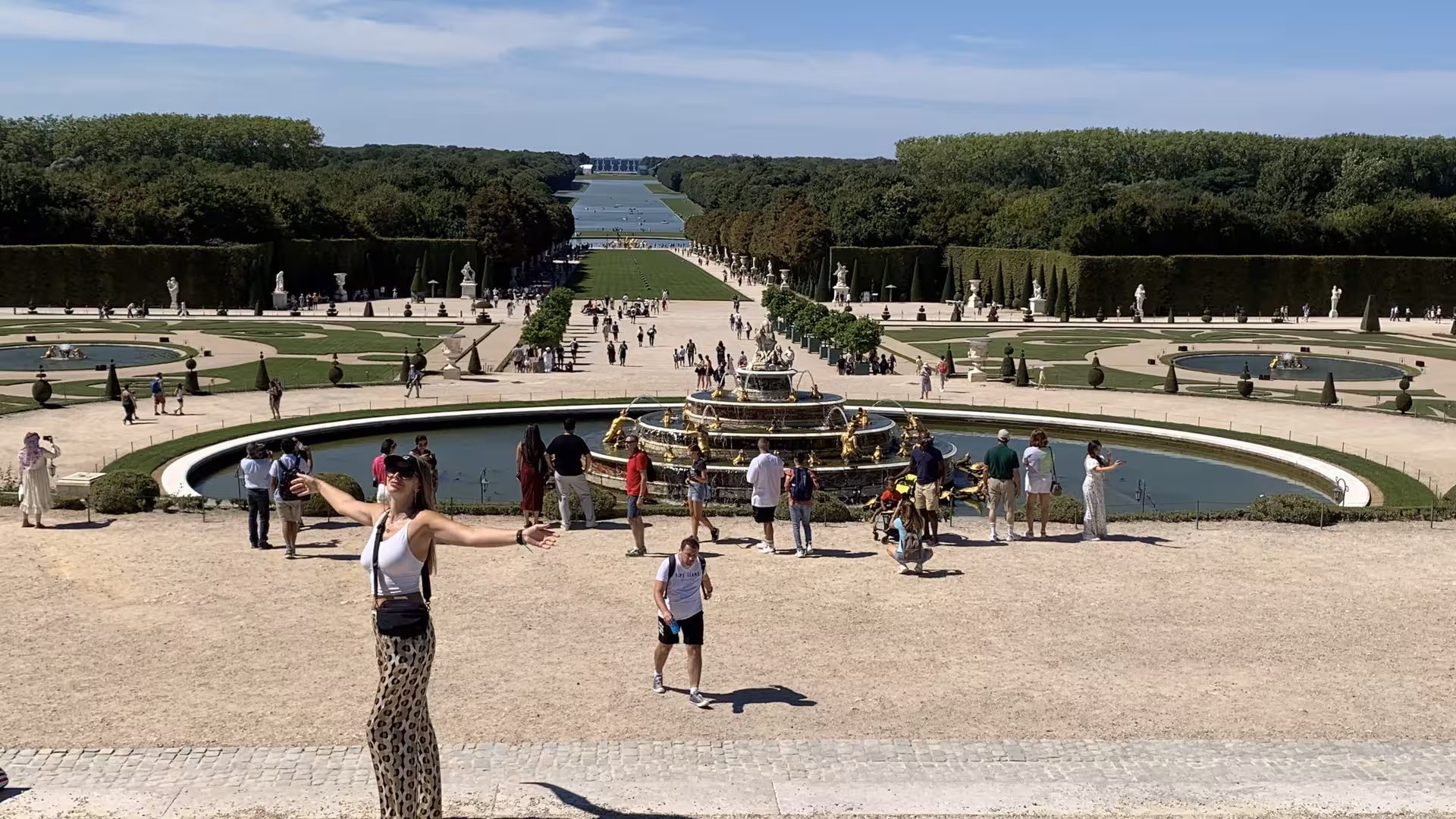 Tourists at the Latona Fountain in the formal gardens of Palace of Versailles on a sunny day