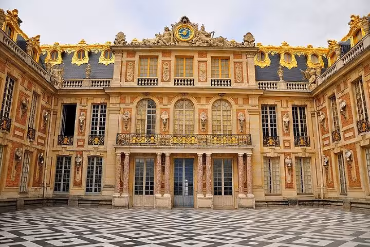 Ornate golden facade of Palace of Versailles with marble courtyard on a private full-day tour from Le Havre.