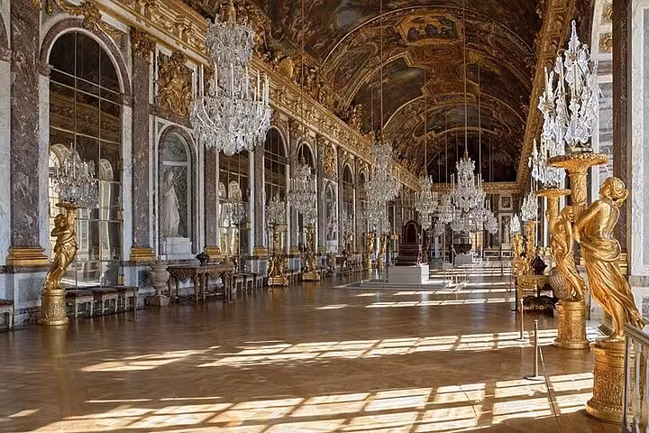 Hall of Mirrors at Palace of Versailles with gilded statues, crystal chandeliers, and ornate ceiling paintings