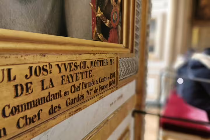 Close-up of historic plaque and framed artwork inside Versailles Palace on guided skip-the-line tour