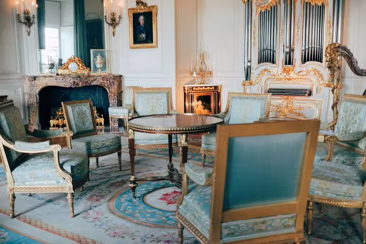 Luxurious interior room at the Palace of Versailles featuring antique furniture and decor on a Paris tour.