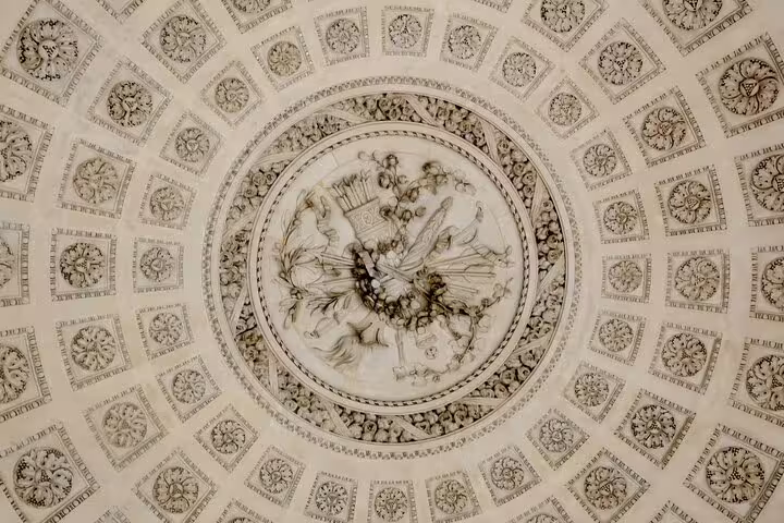 Ornate neoclassical ceiling medallion with floral relief carvings and decorative rosettes at Palace of Versailles