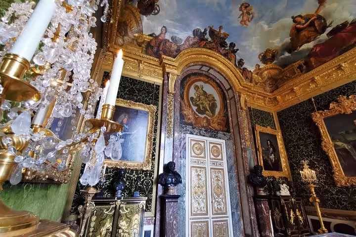 Ornate Versailles Palace room with chandelier, painted ceiling and gold decor on guided skip-the-line tour