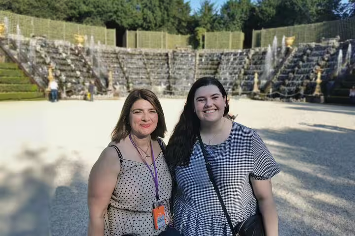 Guests posing by the Versailles Palace Park fountains on a private guided day tour from Paris