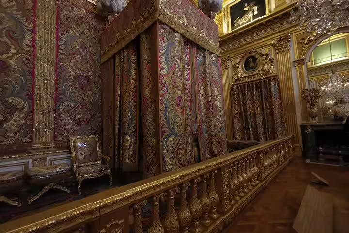 Opulent royal bedroom at Versailles Palace on guided skip-the-line tour, gilded decor and tapestries