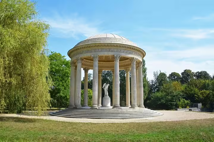 Neoclassical Temple of Love rotunda with marble columns and statue in Versailles garden