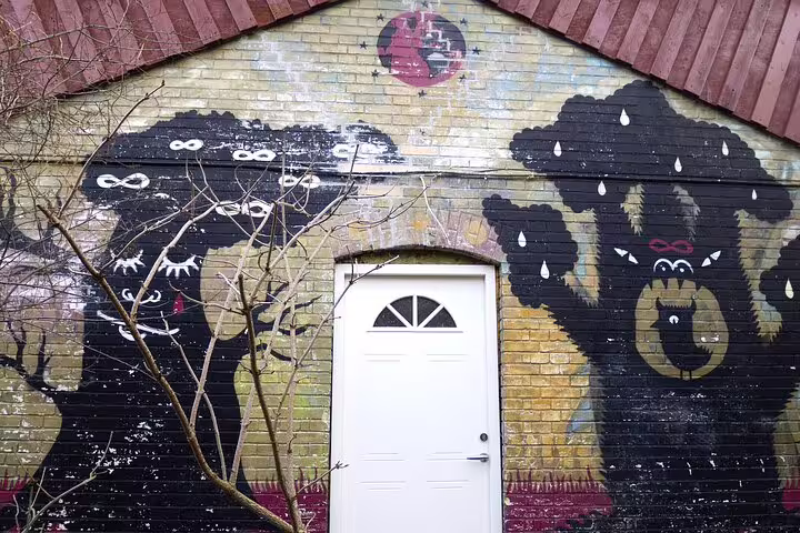 Colorful street art on a building wall in Vesterbro, Copenhagen, depicting whimsical creatures under a red moon.