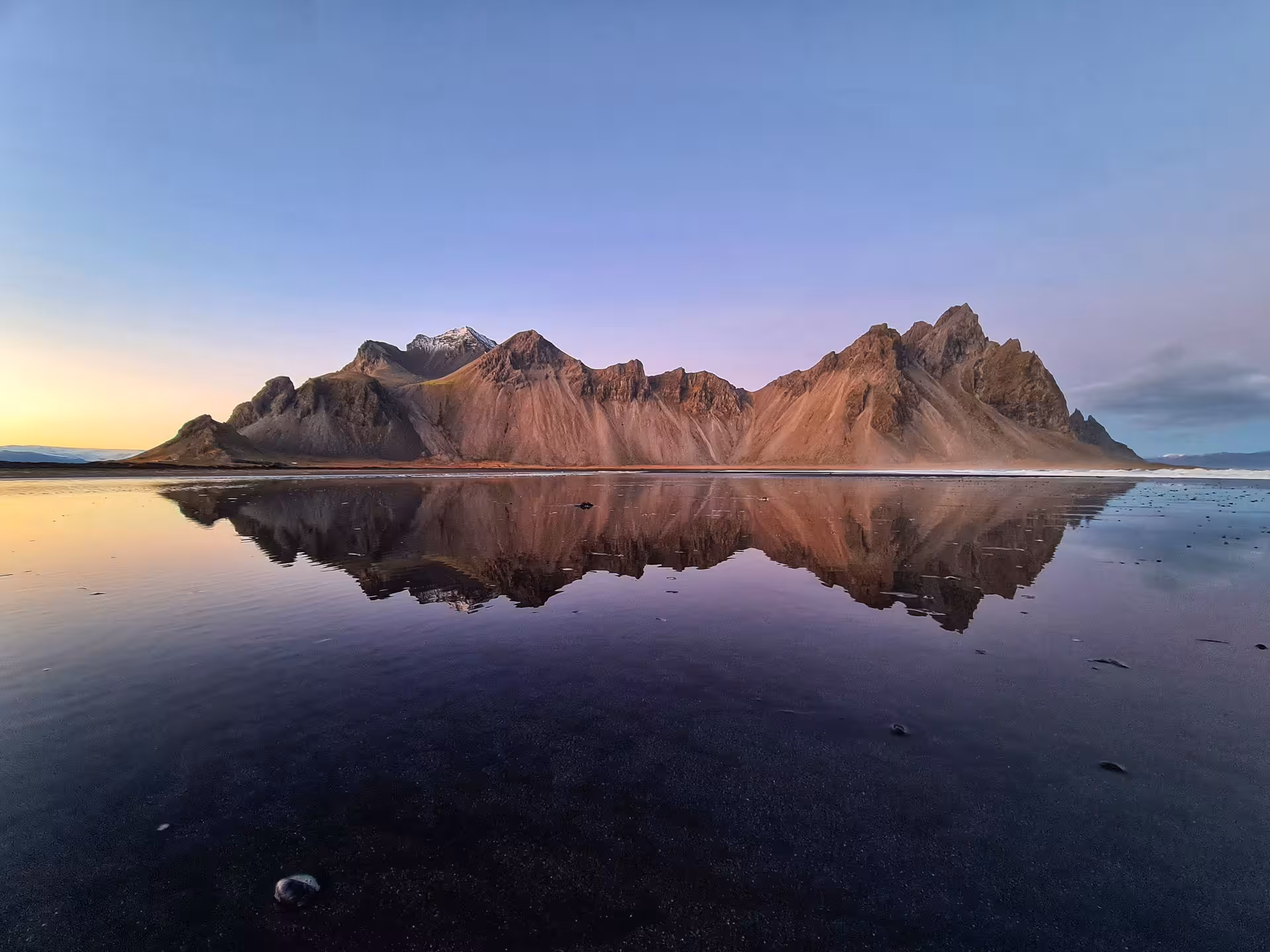 Vestrahorn mountain reflected in black sand beach at sunset near Djupivogur, Iceland