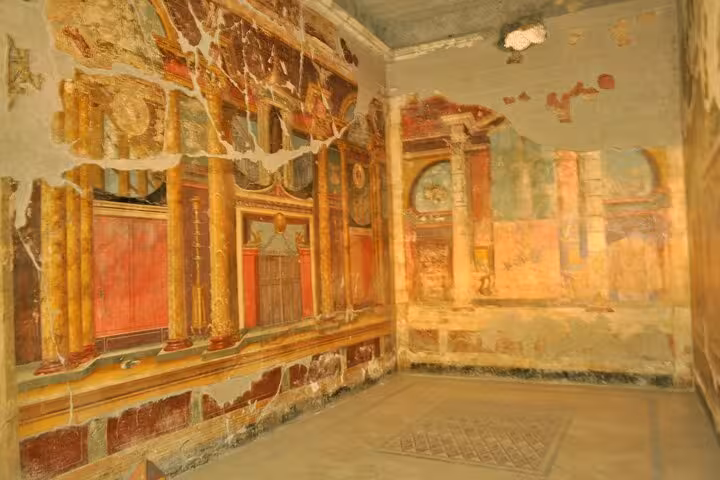 Frescoed walls with vibrant colors and classical architecture in a restored room near Vesuvius.