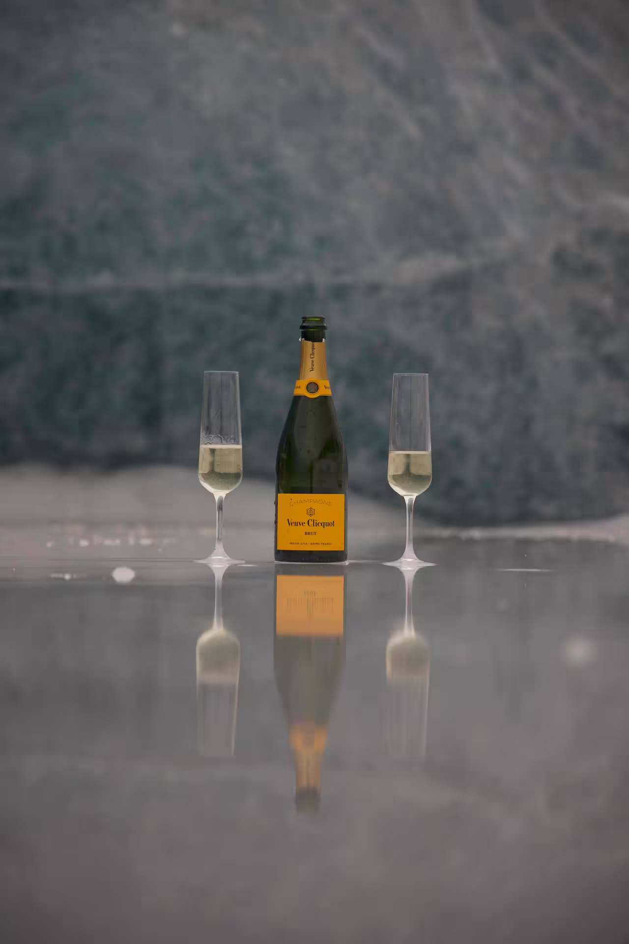 Veuve Clicquot champagne bottle with two flutes reflecting on glacier ice for a luxury elopement experience