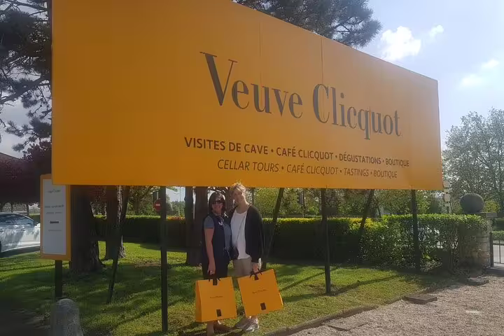 Visitors posing under Veuve Clicquot sign in Reims, a stop on Champagne tasting day trip from Paris with cellar tour