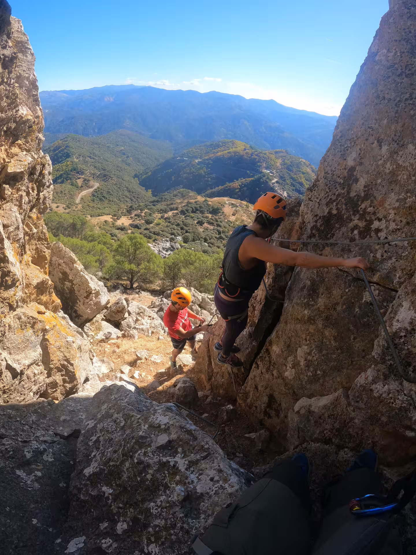 Two climbers traverse Via Ferrata route in Benalauría, enjoying panoramic vistas of Costa del Sol's landscape.